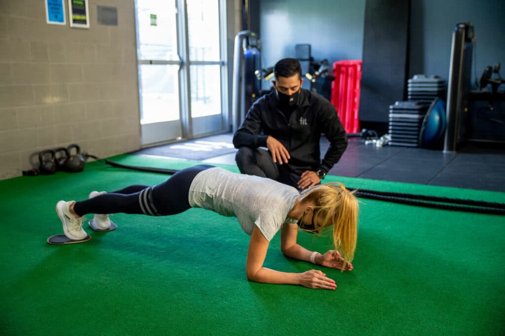 A man and a woman doing push ups in a gym.