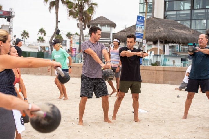 Group working out using kettle bells with fitness trainer