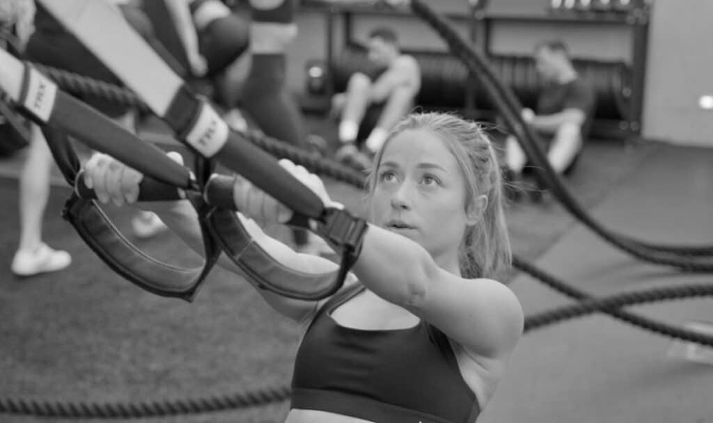 A woman is holding a weighted ball in a gym.