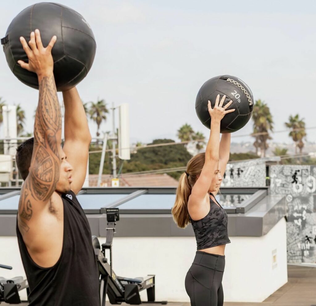 A man and woman lifting weights on a rooftop.