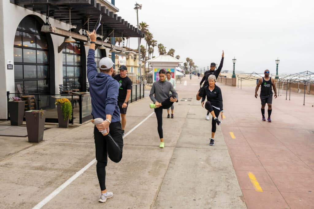 A group of people doing yoga on a sidewalk.