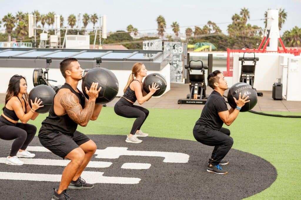A group of people doing squats on a gym floor.