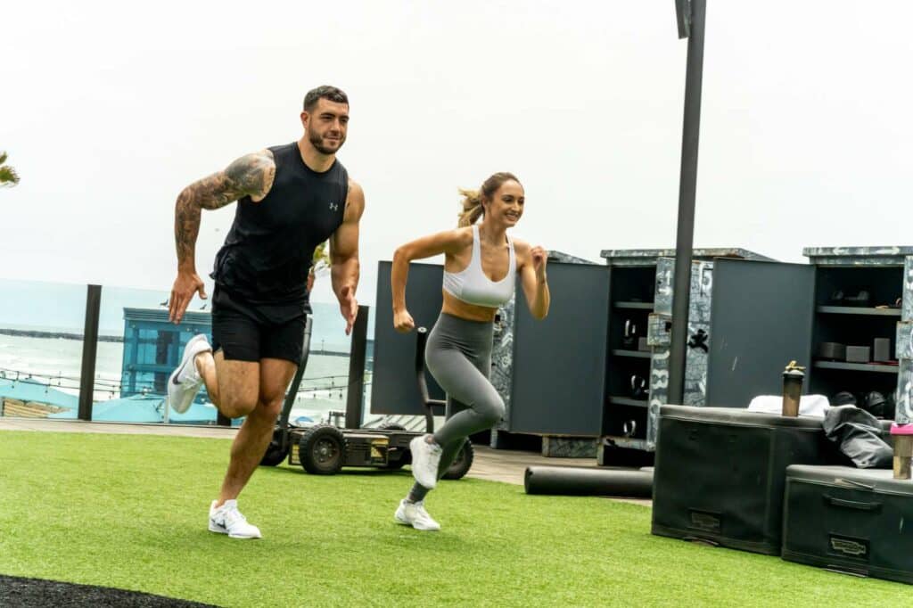 A man and woman on a treadmill in a gym.