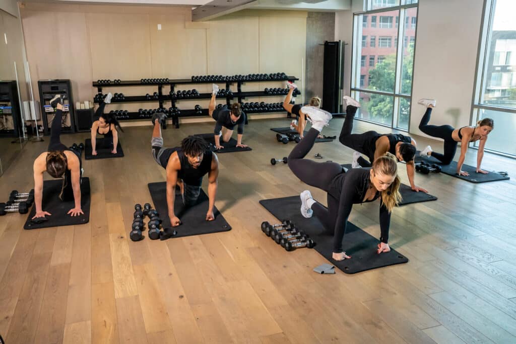 A group of people doing dumbbell exercises in a gym.
